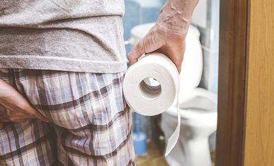 Mand, der står med toiletpapir, lider af hæmorider.