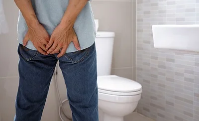 Mand på toilettet har smerter pga. en rift ved endetarmen