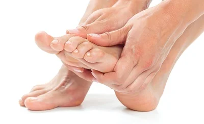 En kvinde mærker efter en nerveknude i sin fod med sine hænder