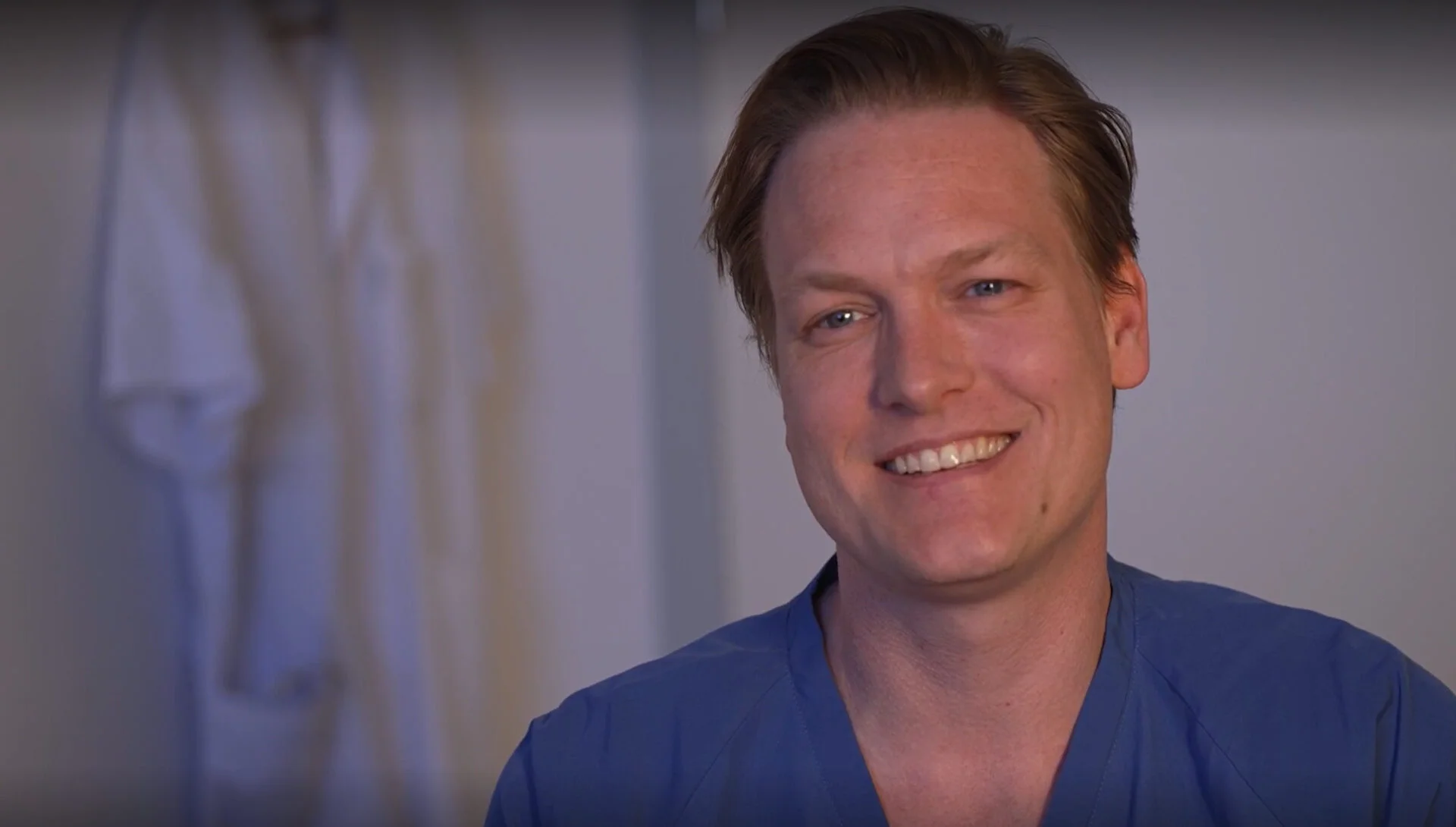 Smilende sidende ung mandlig ortopædkirurg