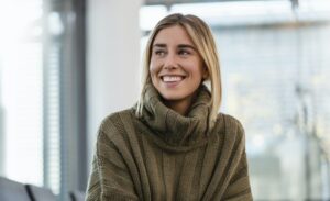 Smiling young woman sitting in waiting area looking around