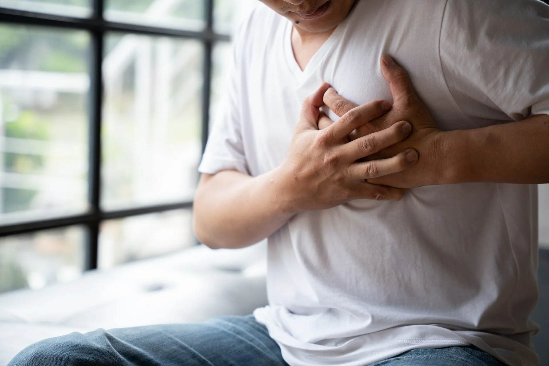 Hands holding chest with symptom heart attack disease, man with heart attack.