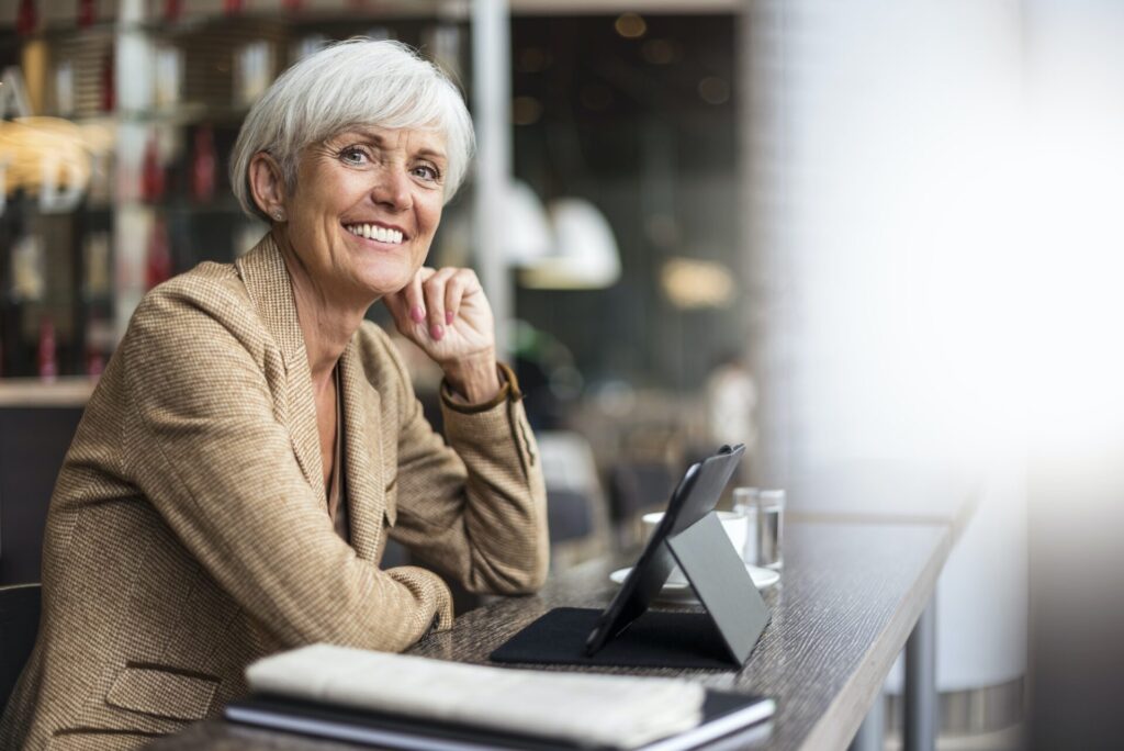 Portræt af smilende ældre forretningskvinde med tablet på en café