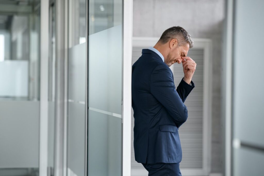Stressed businessman suffering headache in office