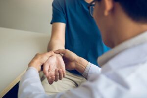 Physical therapist checks the patient wrist by pressing the wrist bone in clinic room.